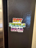 A colorful refrigerator magnet that reads 'HOT PEOPLE READ' in rainbow gradient letters, shown on a dark textured refrigerator door.